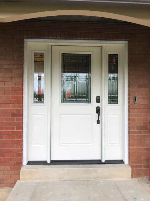 White front door with sidelights set in a brick entry