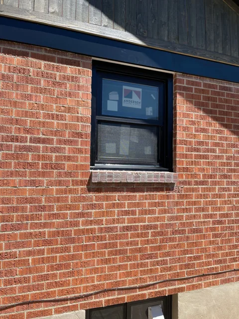 Red brick building with a black framed window.