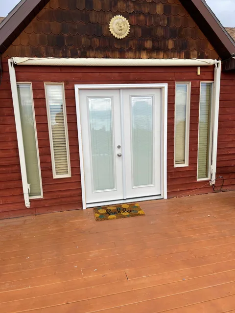 Red building with white double doors, sidelights, and welcome mat.