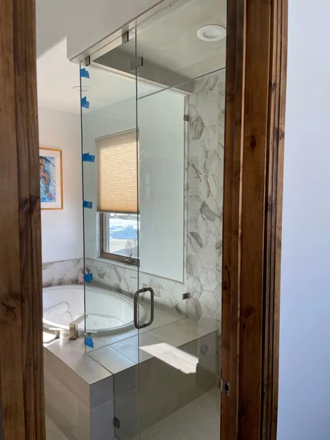 Custom glass shower enclosure with a wood-trimmed doorway